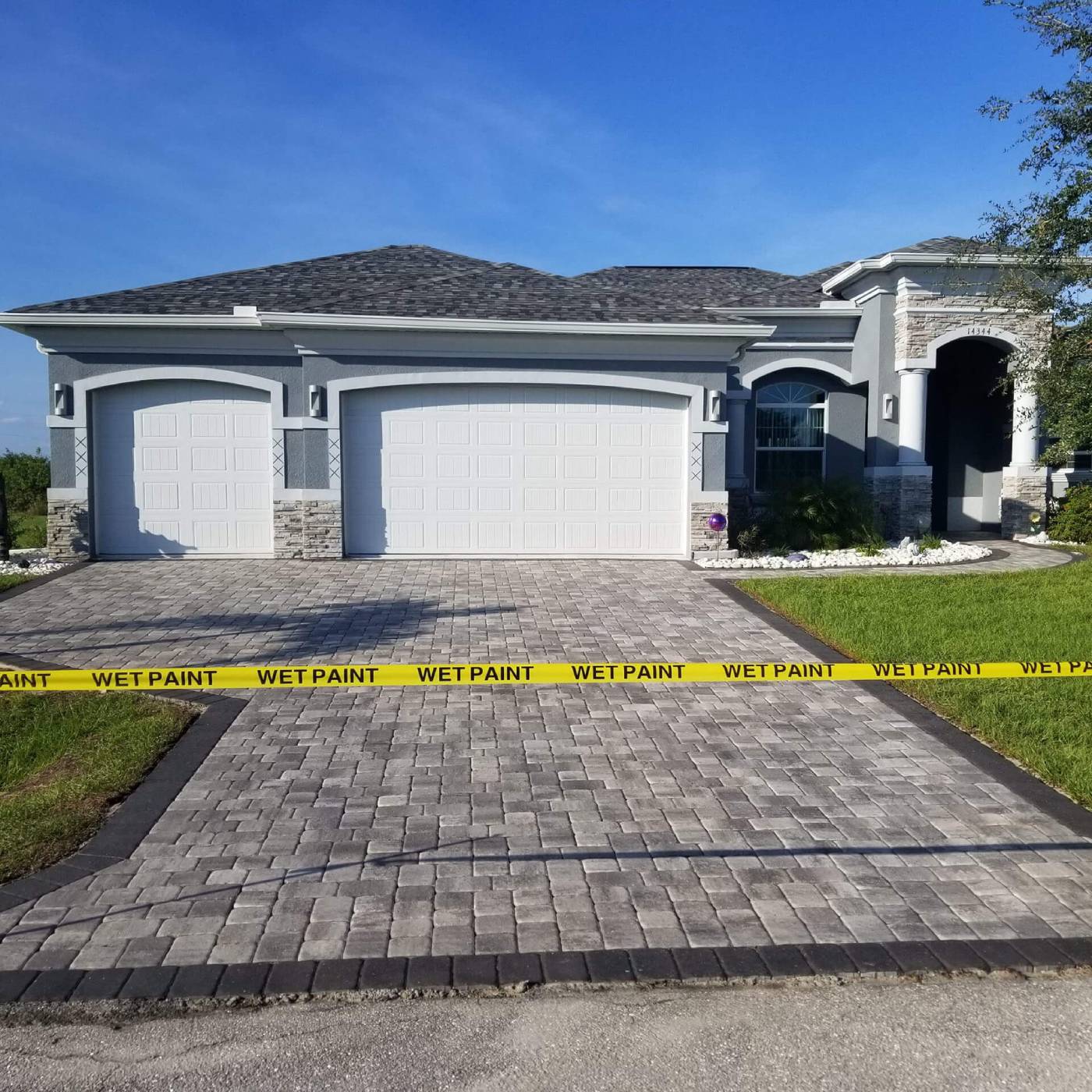 gray house with clean pavers and wet tape