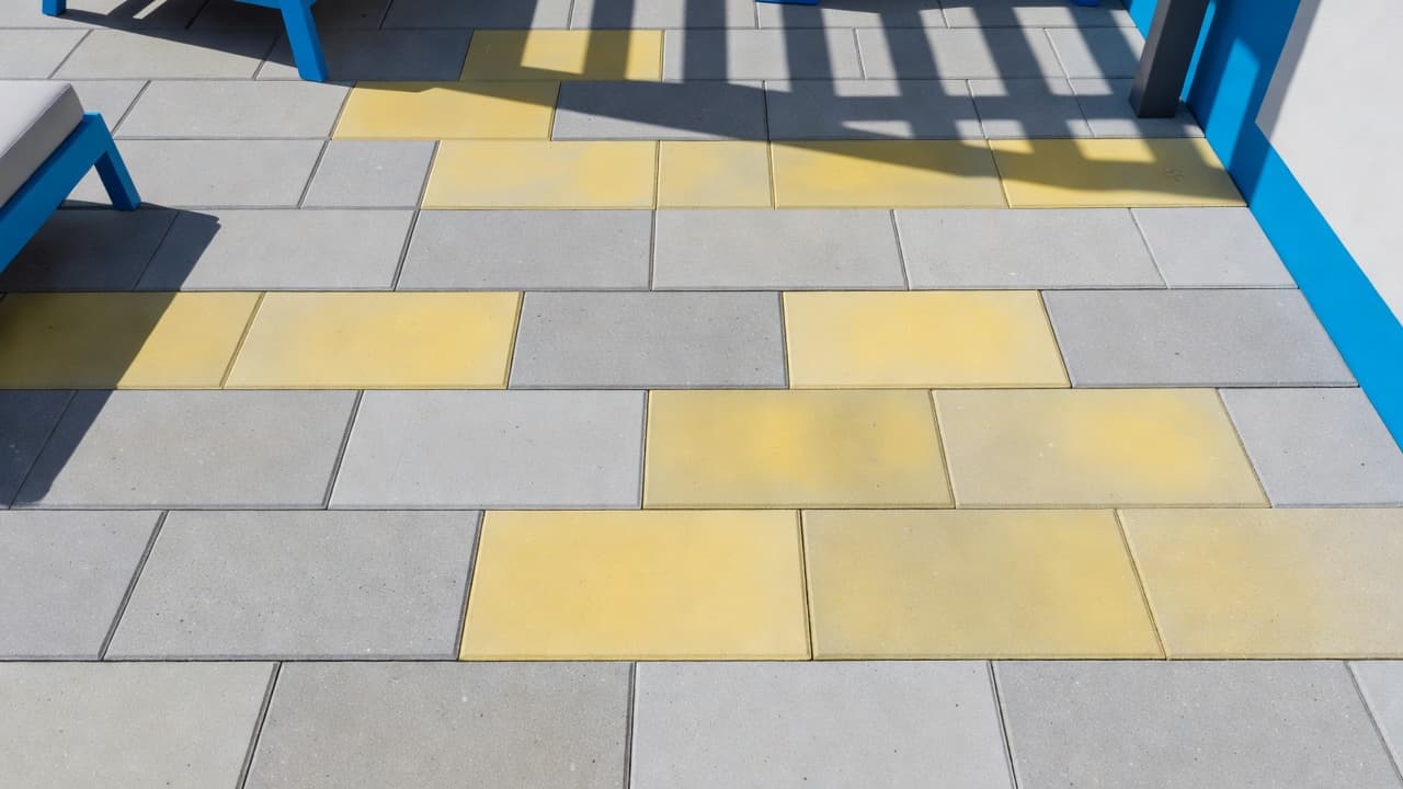 Yellow paver sealer showing hazy discoloration beside clean concrete pavers