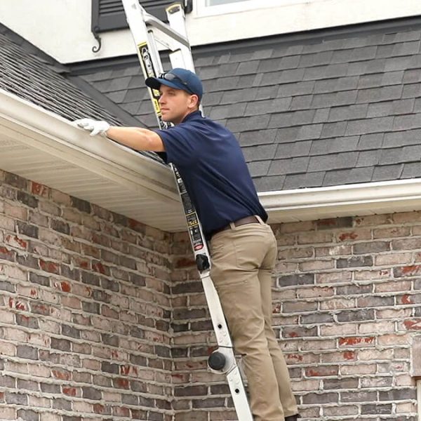 gutter cleaning professional cleaning gutter on ladder in white gloves