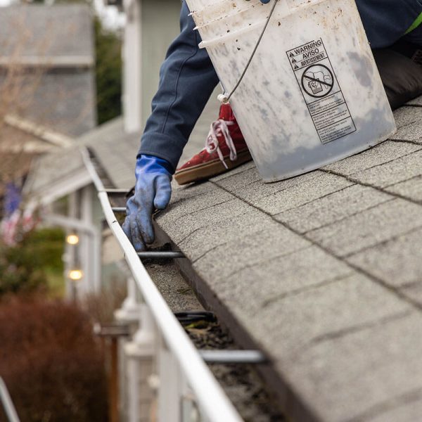 gutter cleaning professional in blue gloves cleaning gutter on