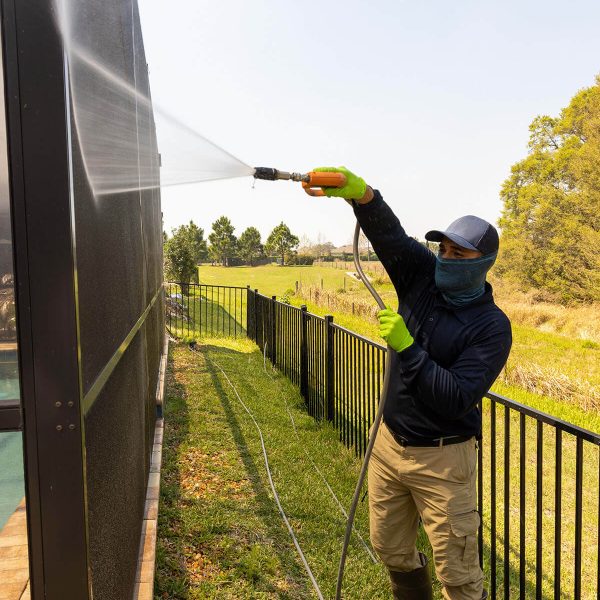 pressure washing professional washing fence with yellow gloves