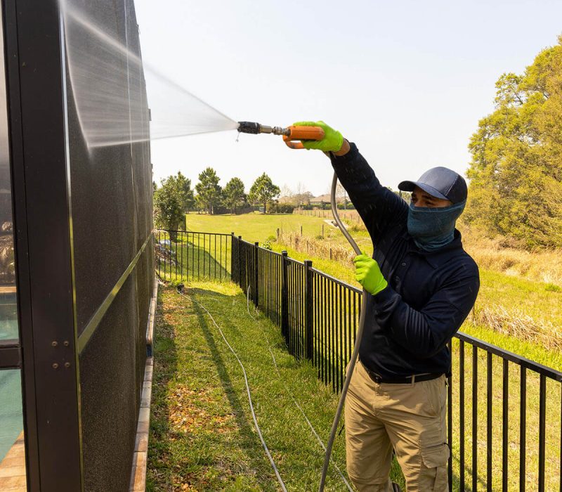 pressure washing professional washing fence with yellow gloves