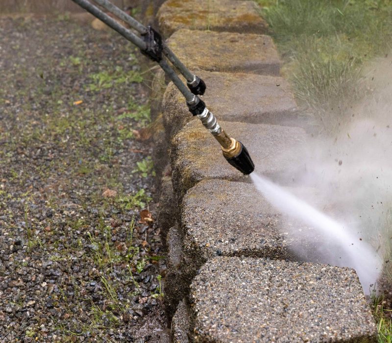 closeup of pressure washer spraying concrete