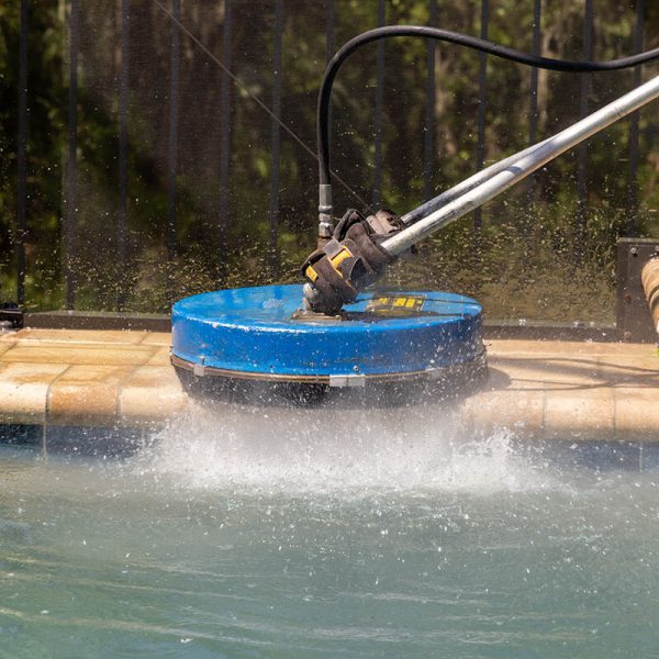 close up of blue pressure washing by pool cleaning pavers