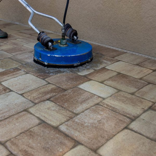 pressure washing professional cleaning pavers with blue pressure washer