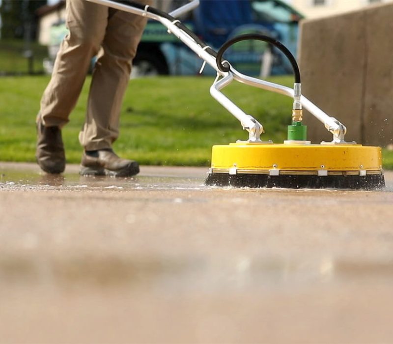 pressure washing professional washing concrete with yellow pressure washer