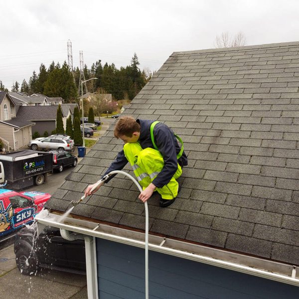 gutter cleaning professional in yellow trousers cleaning gutter