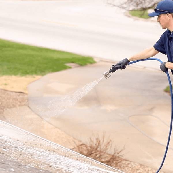 soft wash professional in blue hat washing roof